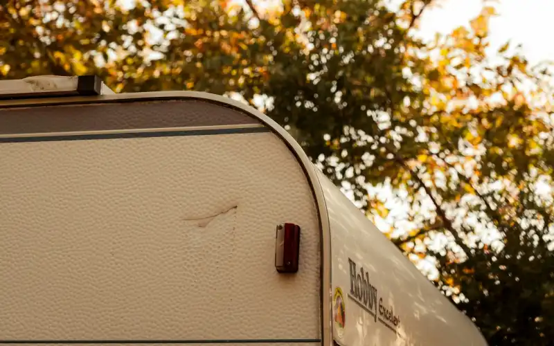 Husvagn framför höstfärgade träd
